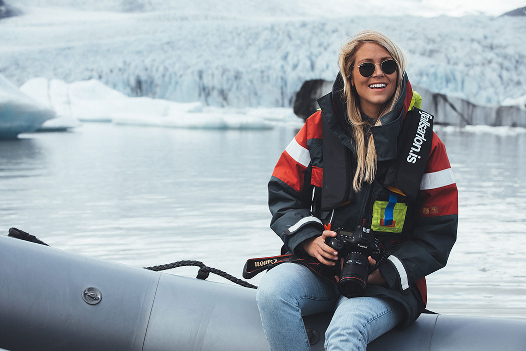 Smiling girl with a camera, against the backdrop of a glacier.