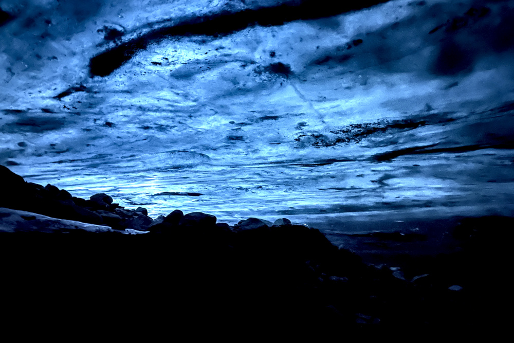 Black rocks under blue ice cave.