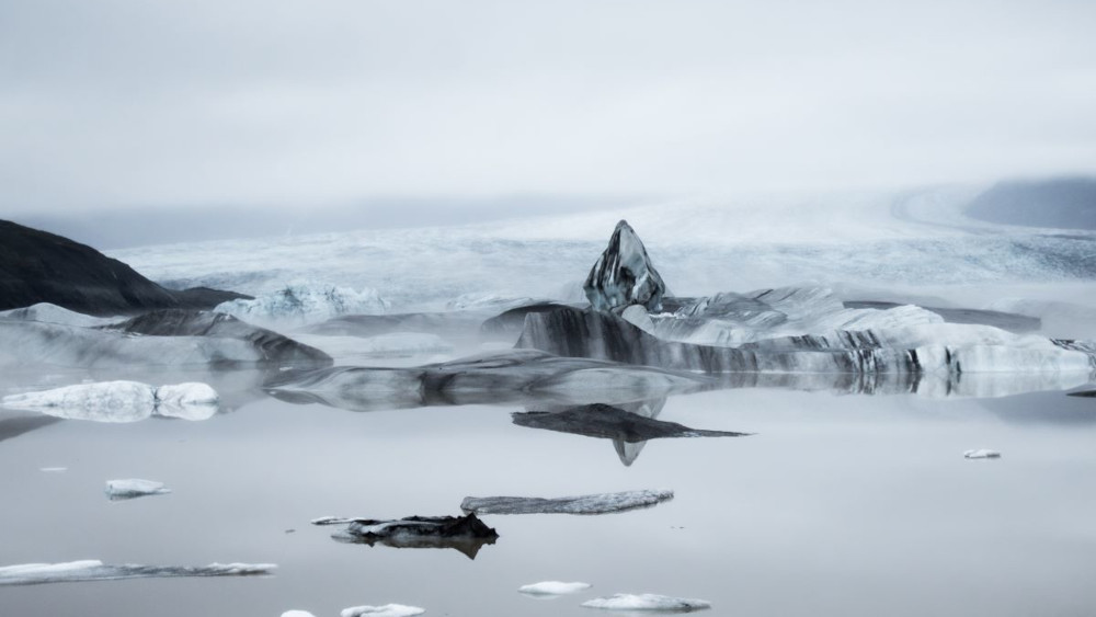 Picture of glacial lagoon called Hoffell lagoon, with many floating icebergs and Hoffelljökull glacier in the background.