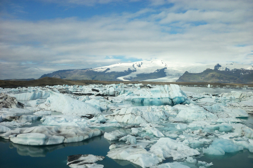 Many icebergs floating around in Jökulsárlón, with Öræfajökull and Fjallsjökull in background.