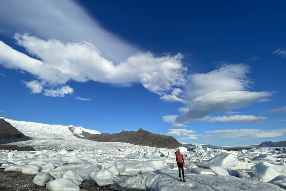 Person standing on a glacier ice ready to make a ice walk with mountain in the background.