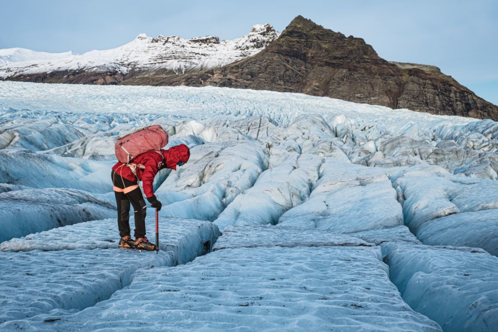 Ultimate Glacier Adventure Trio, guide peering into a crevice of the glacier.
