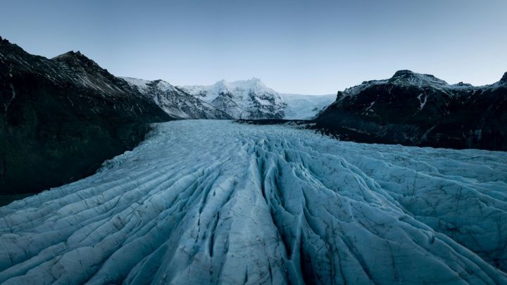 Stunning view of Svínafellsjökull Glacier with jagged ice formations and a distant mountain, under a cloudy sky