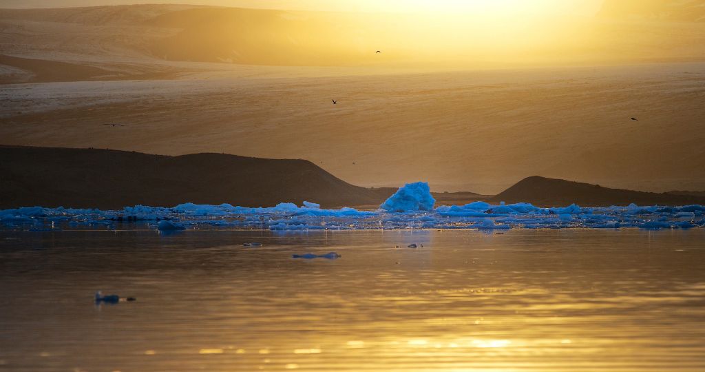 A view of Jökulsárlón glacier lagoon with the midnight sun resting above Breiðamerkurjökull glacier.