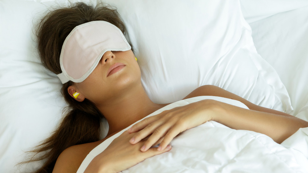 A woman sleeping with a eye mask covering her eyes.
