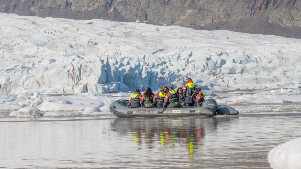 A zodiac boat sailing among the icebergs at Fjallsárlón glacier lagoon.