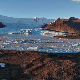 An overview picture of Fjallsárlón glacier lagoon, Fjallsjökull glacier, and towering mountains.