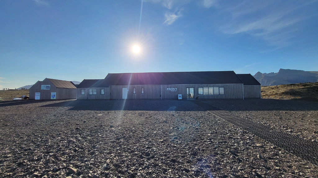 Buildings at Fjallsárlón glacier lagoon with the sun shining behind them.